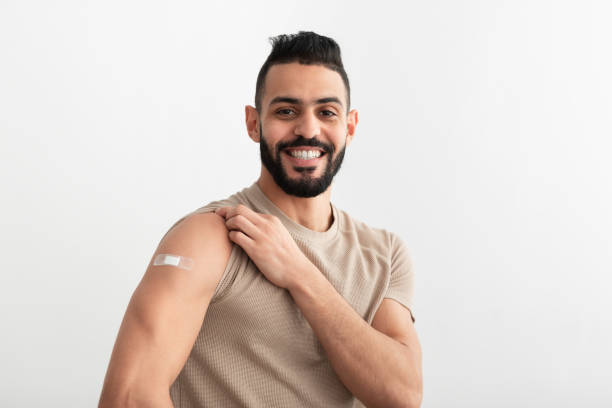 istock Covid vaccination. Arab guy with adhesive plaster on arm after coronavirus immunization posing over white background 1349960681