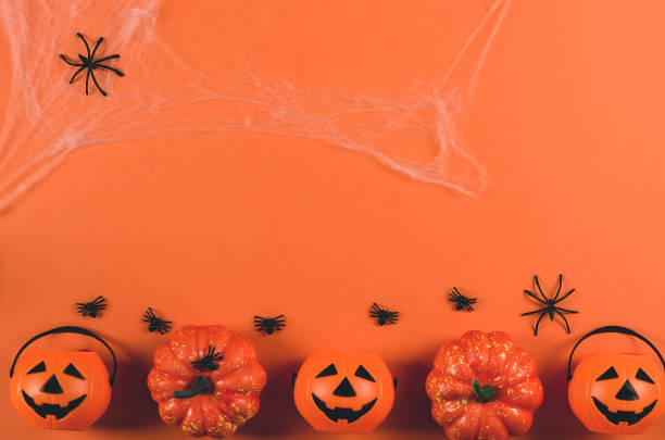 istock Decorations for Halloween on an orange background, copy space. Pumpkins and spiders in a web on an orange background, top view, flat lay. Halloween party. 1349961212