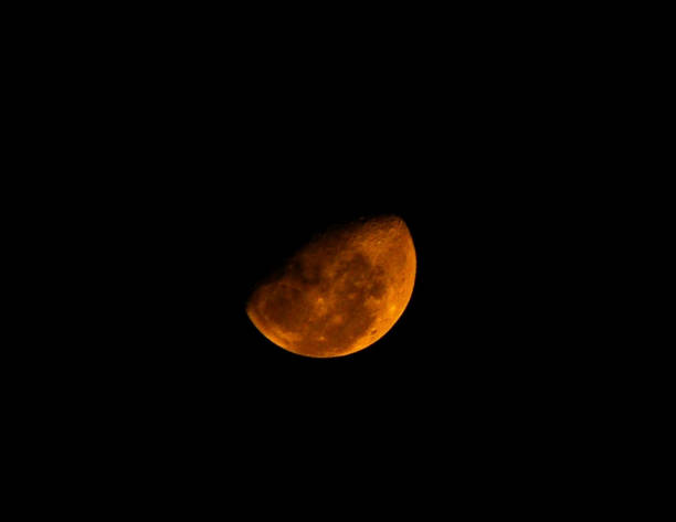 istock Half orange moon glowing on black sky background 1349961792