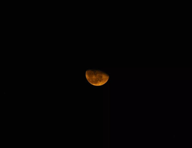 istock Half orange moon glowing on black sky background 1349961795