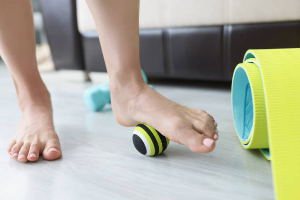 Female legs roll small sports ball on floor at home closeup Female legs roll small sports ball on floor at home closeup. Flat feet treatment concept roller ball stock pictures, royalty-free photos & images