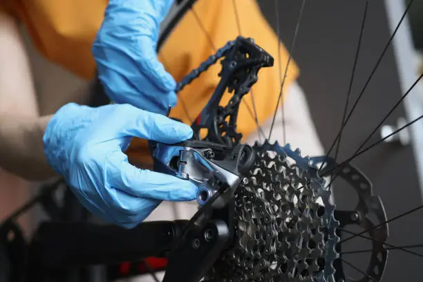Photo of Handyman in rubber gloves fixing brakes of bicycle closeup