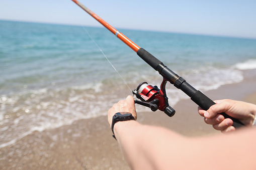 Man fishing with rod on seashore closeup. Hobby fishing concept