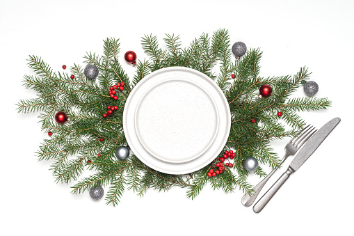 Christmas or New year table setting with empty white plates and cutlery on on spruce branches