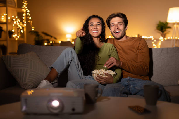 парень и девушка смотрят кино через проектор дома - movies at home стоковые фото и изображения