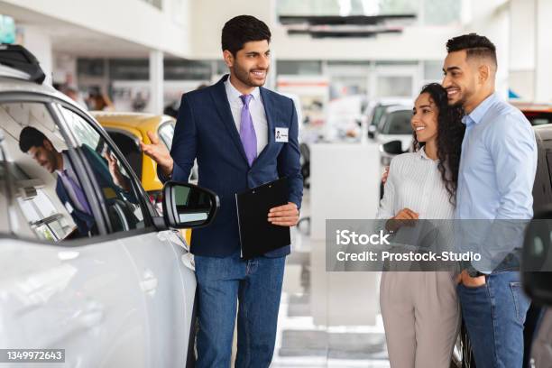 Smiling Middleeastern Couple Looking At White Car Stock Photo - Download Image Now - Car Dealership, Car Salesperson, Car