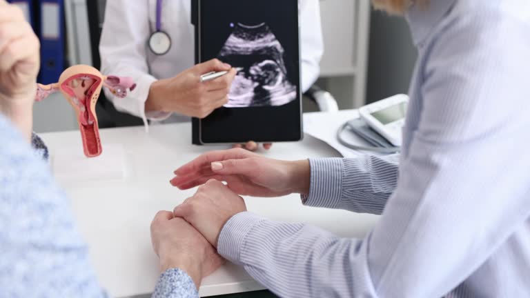 Gynecologist showing result of fetal ultrasound examination on digital tablet to married couple 4k movie