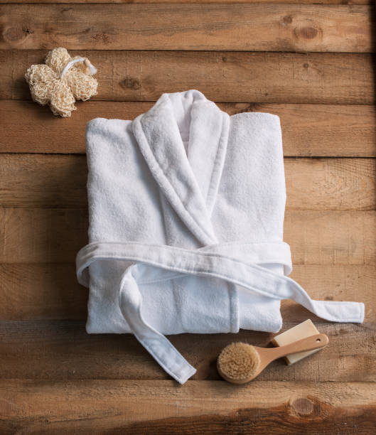 accappatoio bagno sapone e spazzola luffa dietro tavolo di legno - bathrobe foto e immagini stock