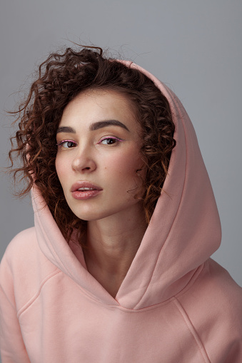 Portrait of pretty young woman wearing pastel pink hoodie