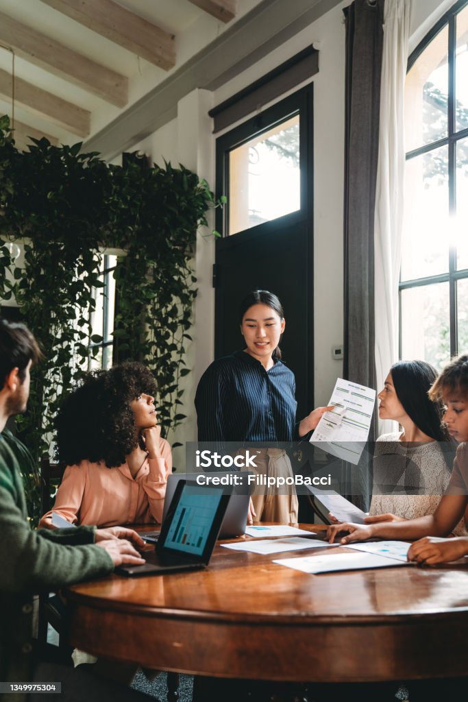 Business meeting of young adult people in a modern loft Business meeting of young adult people in a modern loft. A woman leader is talking about the new strategies of the business. Teamwork Stock Photo