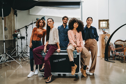 Portrait of a creative group of people in a modern loft with photographic equipment in the background. They are looking at camera. Multi ethnic group of young adult people.