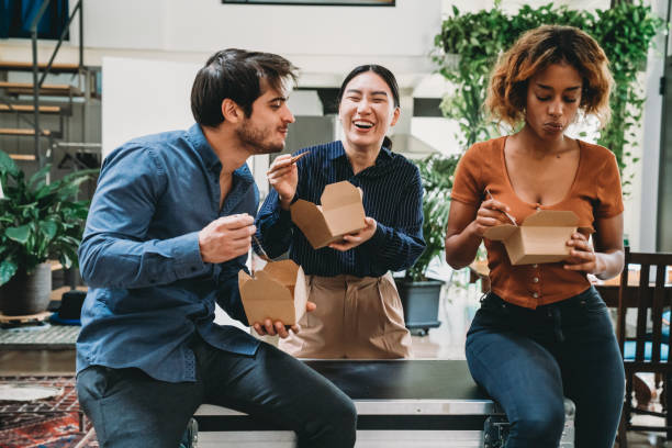 equipe criativa de jovens adultos durante uma pausa para almoço em seu espaço de coworking - hora de almoço - fotografias e filmes do acervo