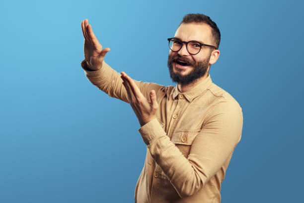 istock Young man in beige shirt gesturing throwing away money, having fun in studio 1349975787