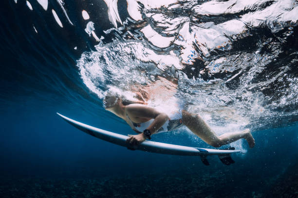 istock Surfer woman with surfboard dive underwater with ocean wave. 1349979164