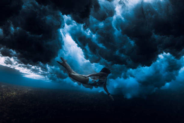 istock Woman swim underwater with ocean wave. Duck dive under wave 1349979183