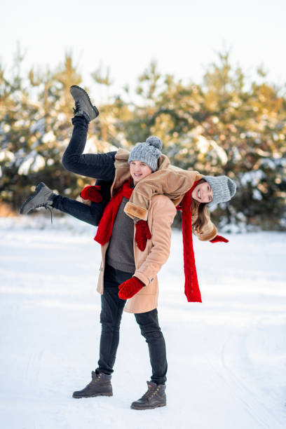 istock Handsome guy carrying laughing girlfriend on his shoulder, winter shot 1349979808