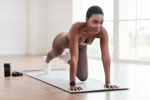 Workout Routine. Fit active athletic black woman doing mountain climbers exercise on yoga mat, strong sporty female in sportswear training abs core muscles in gym, fitness studio or at home