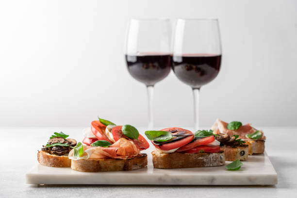 Bruschetta set for wine Bruschetta set with prosciutto and basil, tomatoes and mozzarella, camembert and berries, mushrooms and parsley on marble board. Antipasto open sandwich appetizer restaurant food canapes appetizers stock pictures, royalty-free photos & images