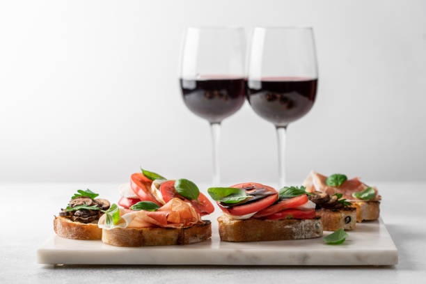 Bruschetta set for wine Bruschetta set with prosciutto and basil, tomatoes and mozzarella, camembert and berries, mushrooms and parsley on marble board. Antipasto open sandwich appetizer bruschetta stock pictures, royalty-free photos & images