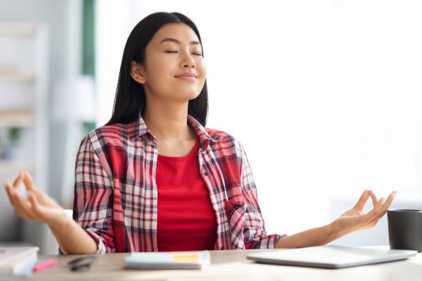 Zen. Calm Young Asian Woman Meditating At Desk In Home Office Zen. Calm Young Asian Woman Meditating At Desk In Home Office, Smiling Millennial Freelancer Lady Sitting With Closed Eyes And Keeping Hands In Mudra Gesture, Dealing With Stress And Anxiety meditation room office stock pictures, royalty-free photos & images