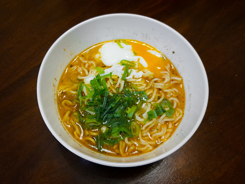 Indonesian instant noodle served with chopped green onion and egg benedict
