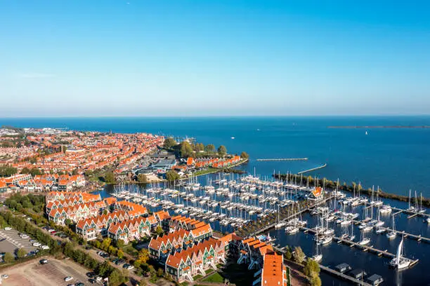 Aerial drone view of typical modern Dutch houses and marina in harbor from above, architecture of port of Volendam town, North Holland, Netherlands