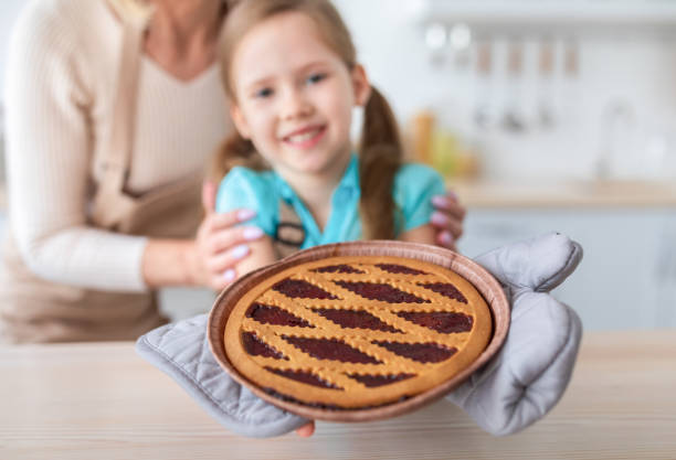 szczęśliwa starsza kobieta i jej wnuczka pokazujące ciasto z dżemem - grandmother pie cooking baking zdjęcia i obrazy z banku zdjęć