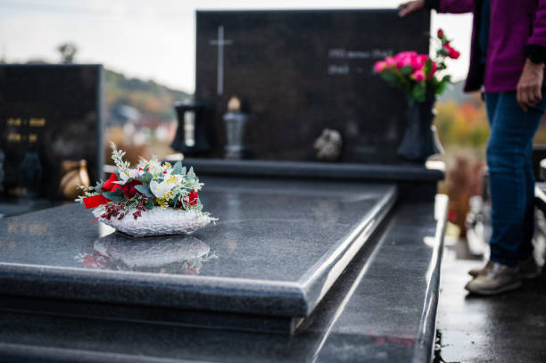 墓の上の花といくつかの敬意を払う女性 - grief women selective focus outdoors ストックフォトと画像