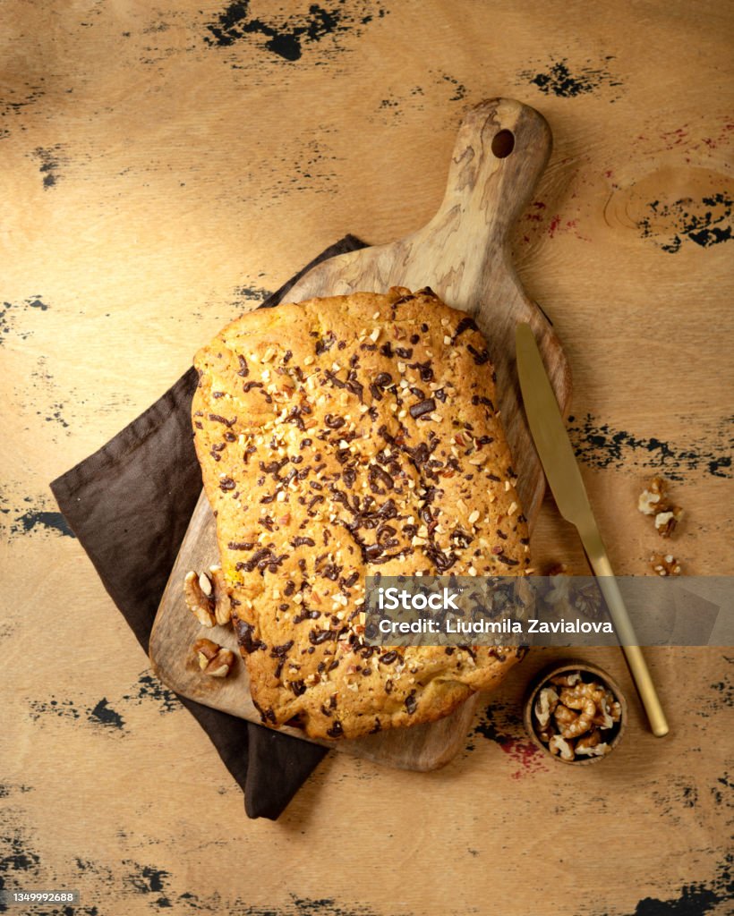 Domácí dýňový koláč s vlašskými ořechy a čokoládou na dřevěné servírovací desce s výhledem shora. Podzimní tradiční sladké pečivo - Bez autorských poplatků Barevný obrázek Stock fotka Domácí dýňový koláč s vlašskými ořechy a čokoládou na dřevěné servírovací desce s výhledem shora. Podzimní tradiční sladké pečivo - Bez autorských poplatků Barevný obrázek Stock fotka