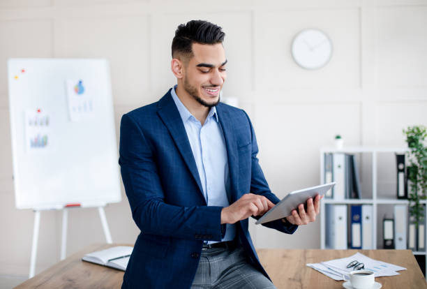 istock Happy millennial Arab guy using digital tablet, studying or working remotely, having online conference at office 1349993027
