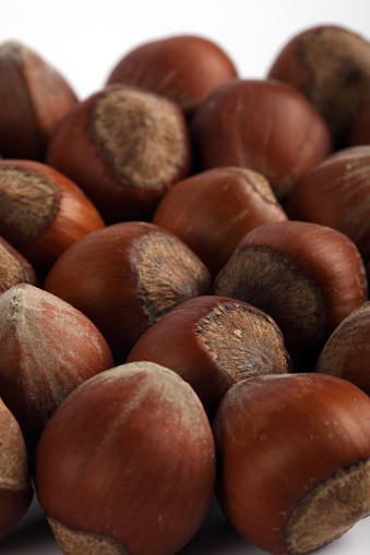 Close-up of fresh shelled hazelnuts isolated on white background. Harvest, hazelnut varieties, organic farming, vegetarian snack, nuts and healthy foods. Empty copy space for text message, vertical.