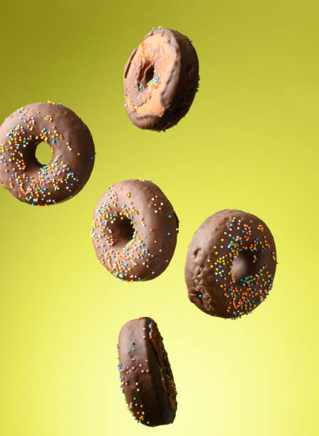 istock chocolate round donuts with multicolored sugar sprinkles levitate on a green background 1350003739