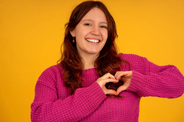 istock Young woman smiling while making a heart with her hands. 1350004443