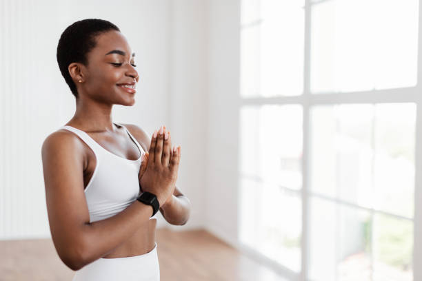 istock Black woman meditating in prayer pose with closed eyes 1350008652