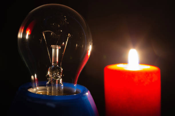 istock A switched off light bulb illuminated by the light of a burning candle in complete darkness. 1350008682