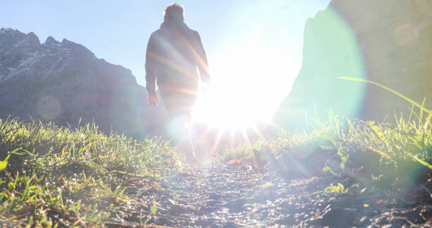 istock Man hikes along grassy mountain ridge at sunrise 1350008700
