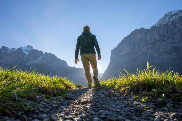 Photo of Man hikes along grassy mountain ridge at sunrise