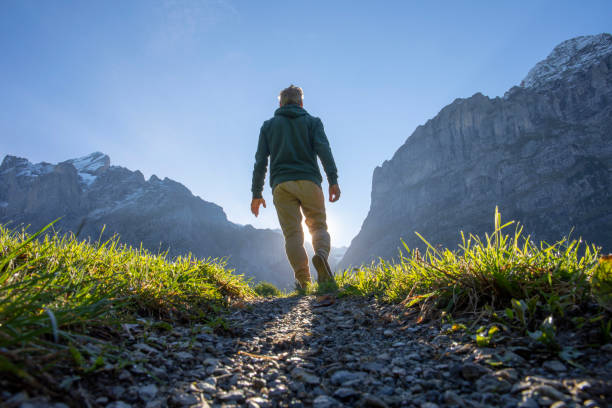 man hikes along grassy mountain ridge at sunrise - trail imagens e fotografias de stock