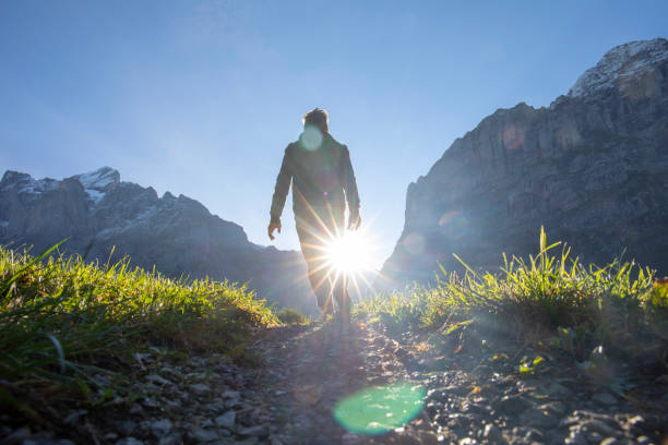 Man hikes along grassy mountain ridge at sunrise