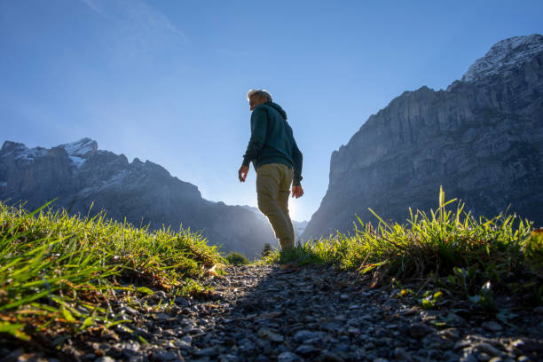 Man hikes along grassy mountain ridge at sunrise