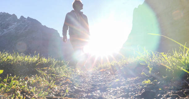 istock Man hikes along grassy mountain ridge at sunrise 1350008724