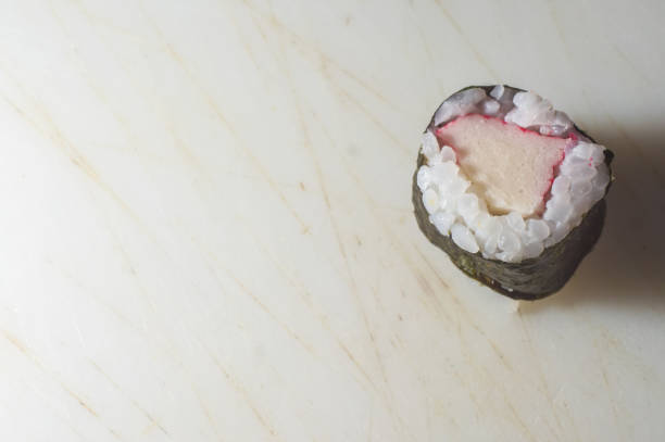 Kani sushi on a white plate with dark background, copy space and selective focus.