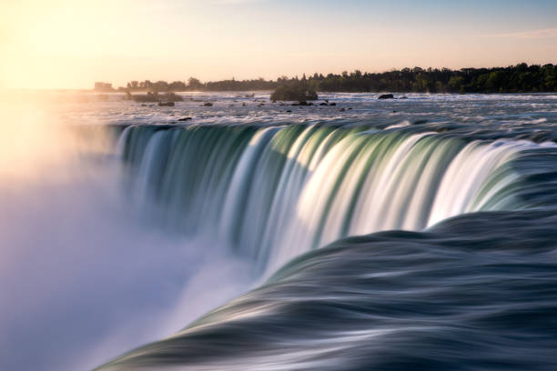 istock Golden sunlight illuminating a powerful dramatic waterfall flowing quickly. Niagara Falls 1350010367