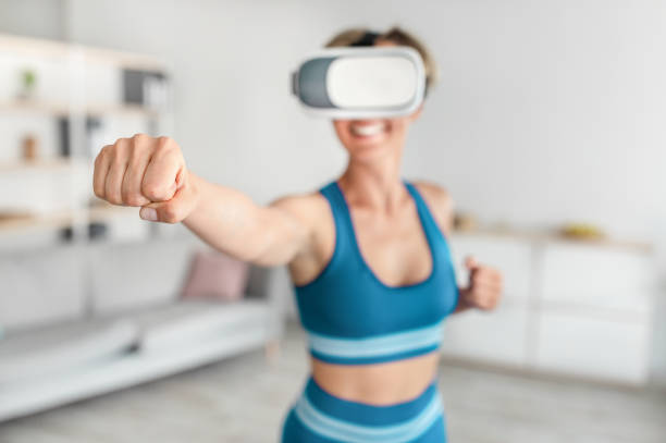 istock Woman in VR headset exercising at home, boxing 1350011437