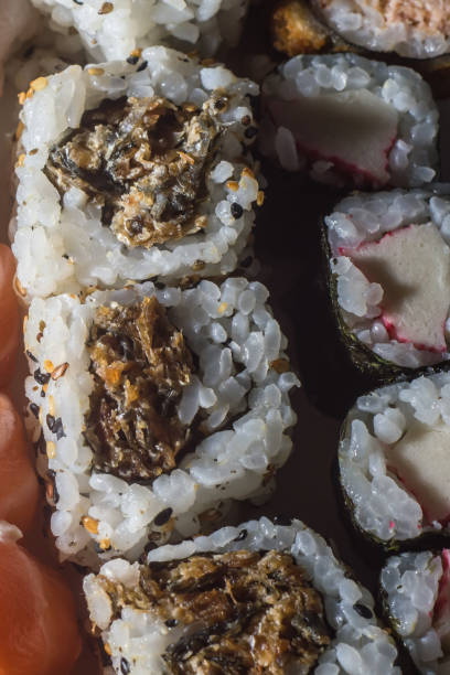 textura de sushi con diferentes tipos de sushi entre ellos: kani, niguiri, uramak - niguiri sushi fotografías e imágenes de stock