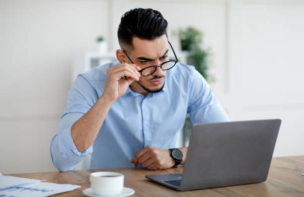 istock Unhappy Arab businessman looking at laptop screen in stress, having problem, making error in business project at office 1350013845