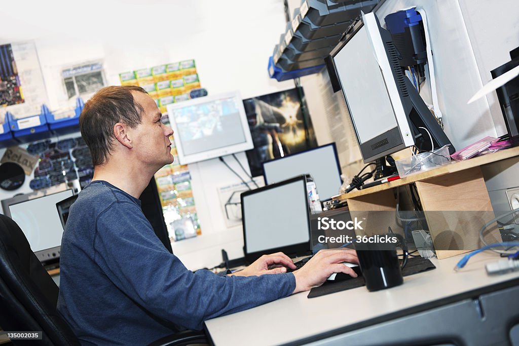 Hacker Hacker behind several computers in a tiny, untidy room Activity Stock Photo