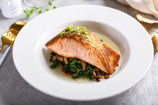 Salmon fillet served with sauteed greens and mushrooms, gourmet plating