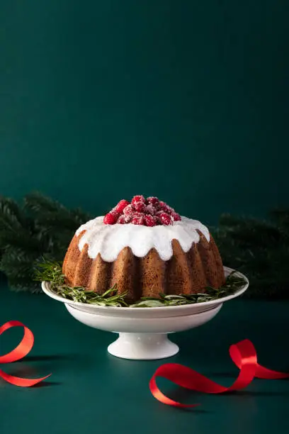 Christmas bundt cake glazed and decorated with sugared cranberries, front view X-mas food concept with copy space for a text