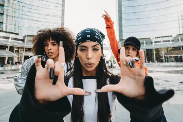 Three female dancer friends are posing in a modern city. Cool attitude. Multi ethnic group of people.